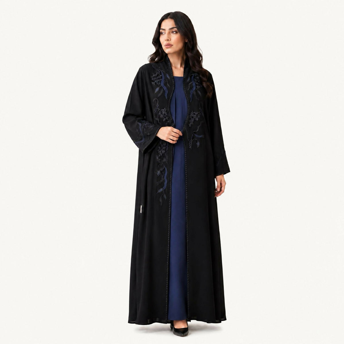 Black crepe abaya with a front panel featuring squares with black embroidery and hand-perforation on the front and back. Fabric works for both summer and winter; hand wash or steam clean.
