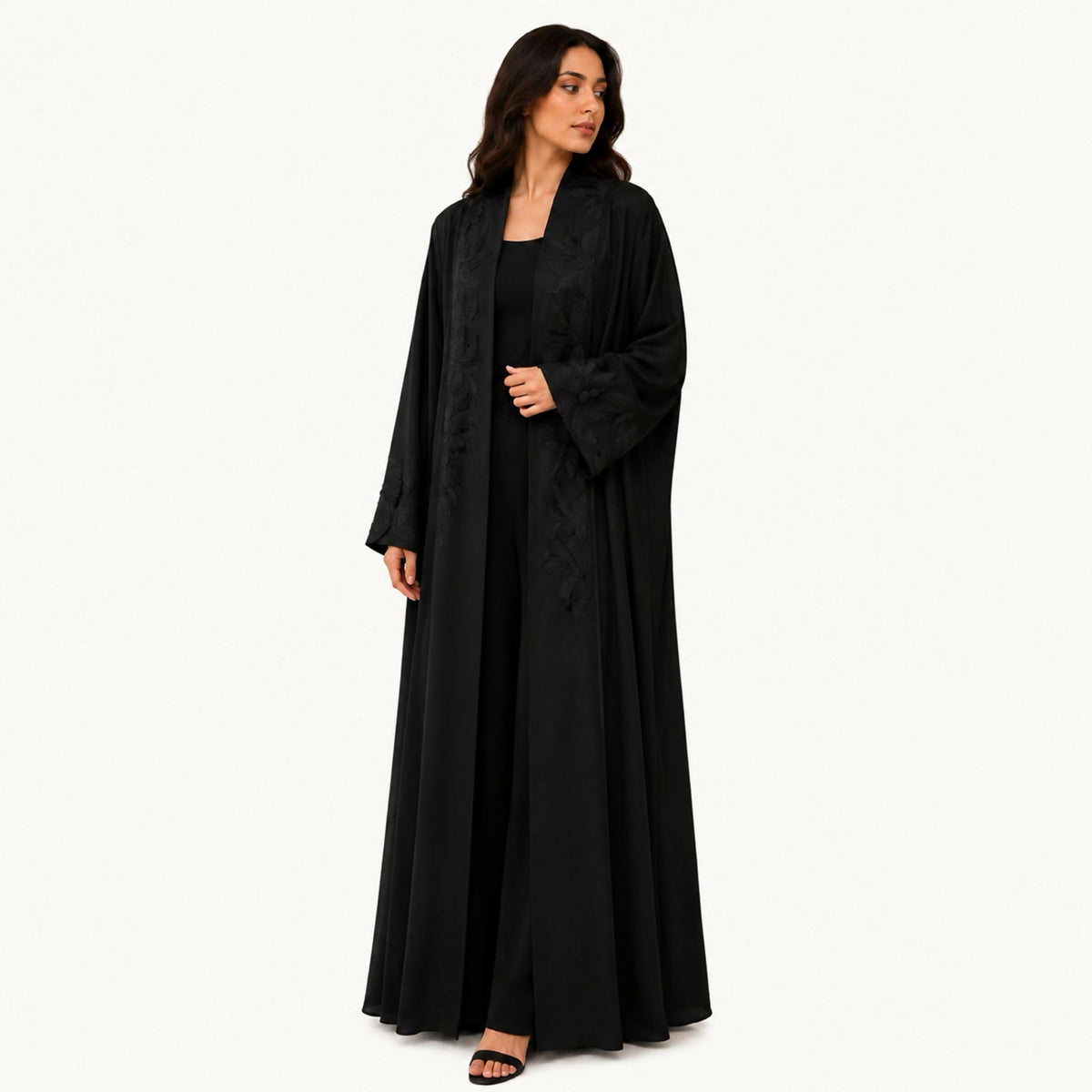 Black crepe abaya with black front embroidery styled as a long front panel, and a back cuff with a button from the same fabric decorated with black embroidery. Hand wash or steam clean.