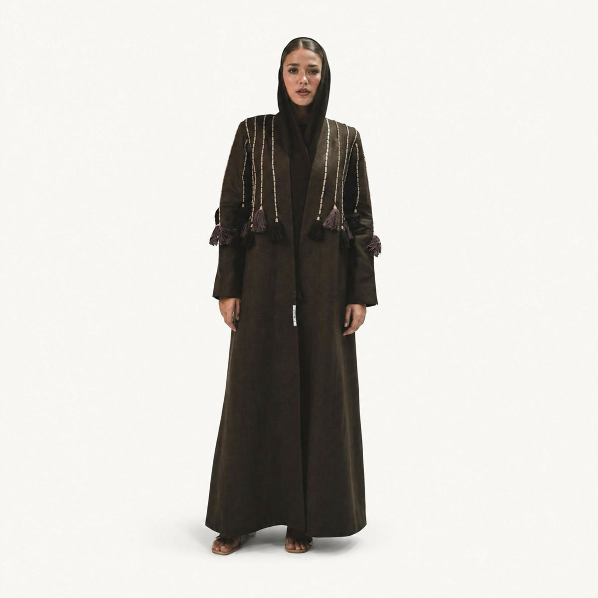 Elegant abaya featuring a refined design, adorned with bold linear embroidery and cascading tassel details across the shoulders and chest. Finished with meticulous handcrafted detailing, it offers a sophisticated contemporary touch, making it perfect for