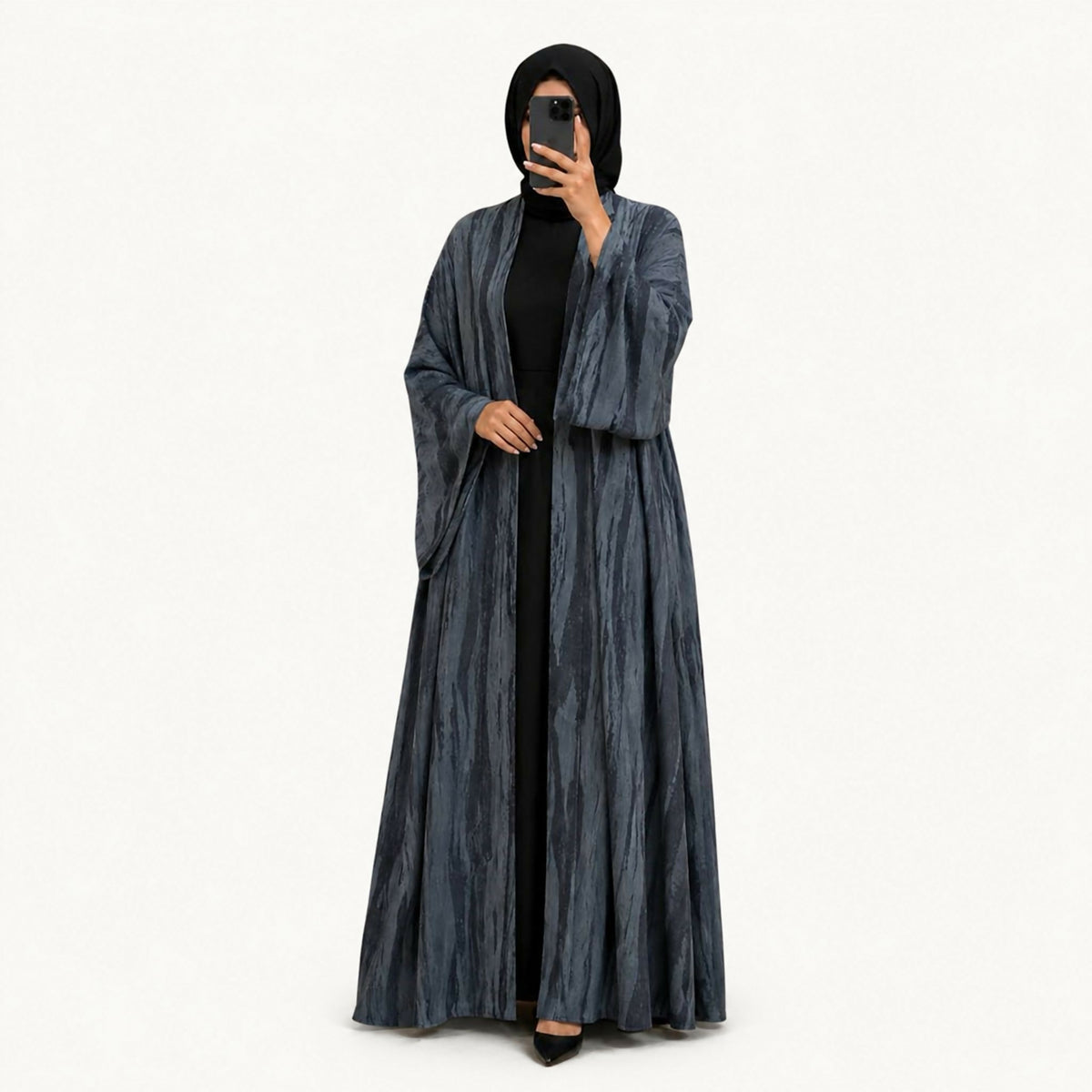 Black crepe abaya with a front panel featuring squares with black embroidery and hand-perforation on the front and back. Fabric works for both summer and winter; hand wash or steam clean.